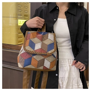 Detail of colorful geometric patchwork leather bag with woven edges and adjustable strap