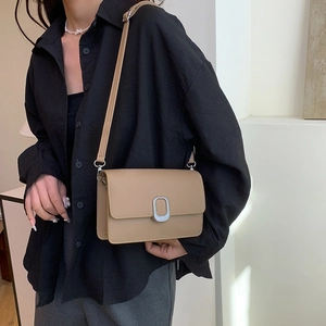 Minimalist khaki square crossbody bag with silver oval buckle shown on a model