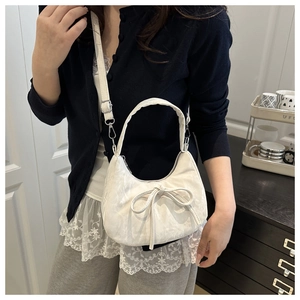 Close-up of white leather crescent bag with bow detail and silver metal hardware