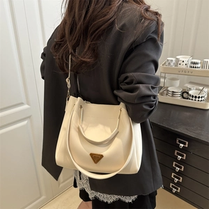 Elegant off-white bucket bag with triangular metal logo and versatile shoulder strap
