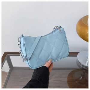 Close-up of light blue quilted shoulder bag with silver chain and metal zipper detail