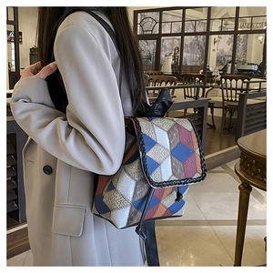 Side view of multi-color geometric patchwork crossbody bag with woven trim on a model