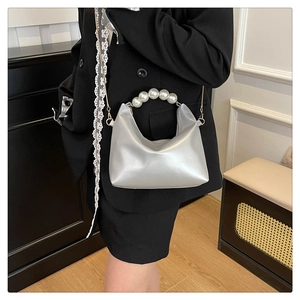 Close-up of silver hobo bag featuring large pearl bead handle and slim chain strap