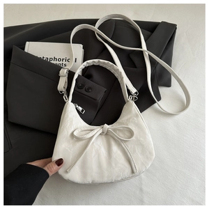 Detail of white half-moon bag with bow knot and pleated texture on black suit
