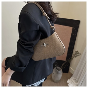 Detail of khaki crocodile pattern crossbody bag with star metal stud and knotted strap