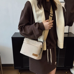 Minimalist beige nylon crossbody bag with adjustable wide strap and leather logo patch