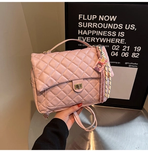 Detail of pink quilted handbag featuring gold metal turn-lock closure and silk scarf decor