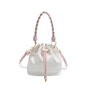 White bucket bag with pink braided handle and gold hardware on white background