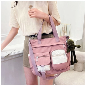 Detail of pink canvas tote featuring functional pockets, shoulder straps, and frog charm