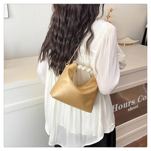 Detailed close-up of light beige handbag featuring a decorative large pearl handle strap