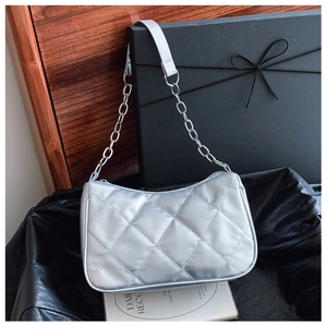 Detail of silver quilted baguette bag with glossy texture and metallic chain strap