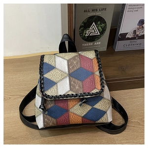 Detail view of colorful patchwork backpack with geometric diamond pattern on wood background
