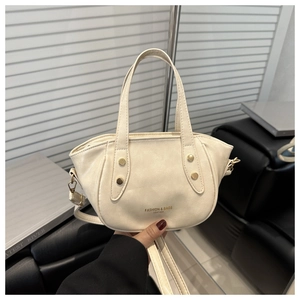 Detailed view of beige rivet handbag with gold hardware and embossed fashion logo
