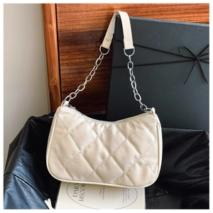 Detailed view of quilted stitching on cream shoulder bag with silver chain strap