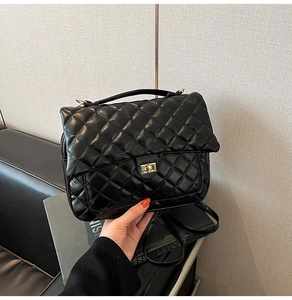 Close-up of black quilted leather tote bag with elegant gold metal twist lock detail