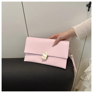 Detailed view of pink envelope clutch with horizontal texture and gold geometric buckle