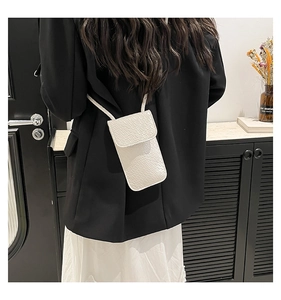Witte crossbody tas met krokodillenprint gedragen door een model voor schaal