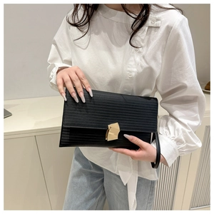 Close-up of black pleated texture envelope clutch bag with gold geometric metal lock