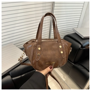 Close-up of vintage brown leather bucket bag with gold rivets and brand lettering detail