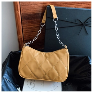 Detail of yellow quilted stitching and silver chain strap on an underarm shoulder bag