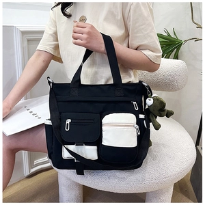 Detail of large black and white canvas tote bag with functional pockets and frog charm