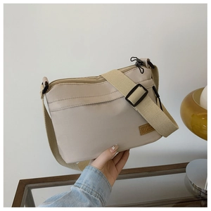 Dettaglio della borsa a tracolla in nylon beige con tessuto impermeabile e tracolla larga