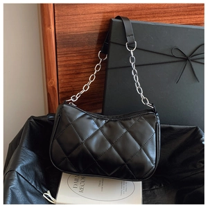 Close-up of black quilted shoulder bag with silver chain strap and metal zipper
