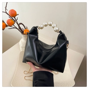 Detail of black hobo bag with large pearl handle and metallic chain strap detail
