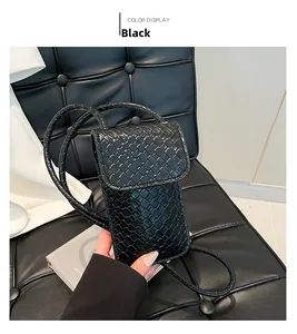 Detail van de zwarte geweven lederen textuur op een compacte crossbody tas
