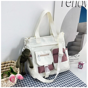 Dettaglio della borsa tote in tela con tasche viola e un ciondolo a forma di rana verde