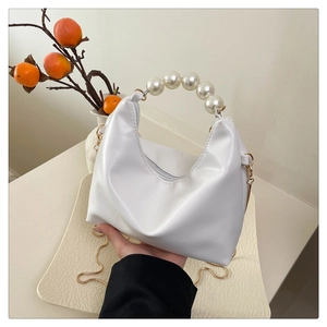 Detail of white PU leather handbag featuring a large faux pearl handle and gold chain