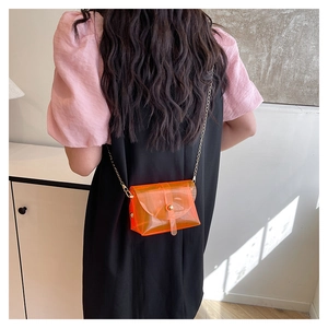 Detail of transparent orange PVC crossbody bag with gold snap and fine chain strap