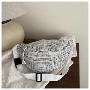 Détail de la texture en tweed d'un sac bandoulière tendance avec sangle blanche réglable