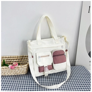 Dettaglio della borsa tote stile coreano con tasche multiple e accenti rosa su tavolo a quadretti