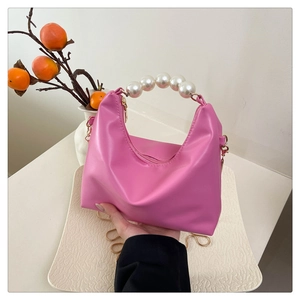 Detail of pink PU leather pillow bag with elegant pearl handle and gold chain strap