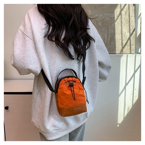 Detail view of orange canvas and brown leather crossbody bag with drawstring