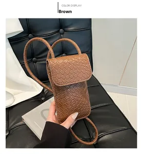 Detail van de bruine geweven textuur en vintage klep van de verticale mini-crossbody tas