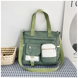Dettaglio della borsa in tela verde scuro con design multitasche e tracolla regolabile