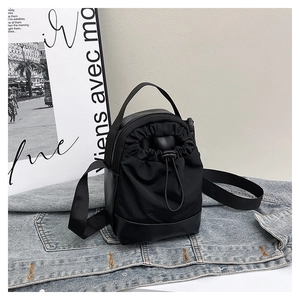 Close-up of black nylon crossbody bag with drawstring pocket on denim background