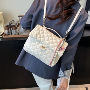 Chic quilted cream tote bag with gold twist lock and woven tassel shown on a model