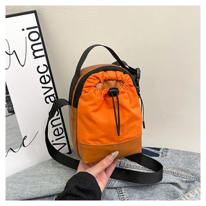 Detail of a two-tone orange and brown bucket bag with adjustable strap and drawstring