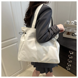 Detailed side view of large white nylon tote bag with black drawstring cords