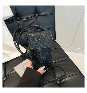 Detail van zwarte geweven textuur op een verticale mini crossbodytas met riempje