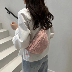 Sac banane à carreaux rose pour femme porté par un mannequin au style urbain décontracté