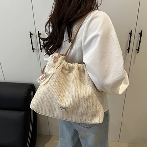 Woven straw shoulder bag with metallic bow detail and floral lace scarf on a model