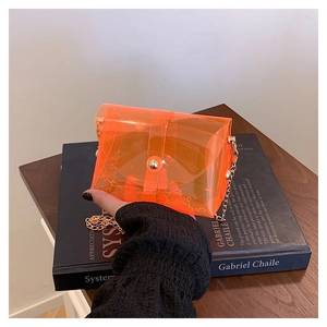 Detail of transparent orange PVC mini crossbody bag with gold chain and metal buckle