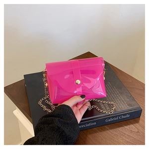 Detail of neon pink jelly bag with gold chain strap and metal clasp on a book