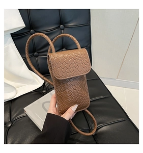 Detail van de bruine geweven textuur en klepsluiting van een stijlvolle crossbody tas dames