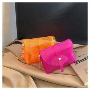 Detail of neon orange and rose red PVC crossbody jelly bags with gold chain straps