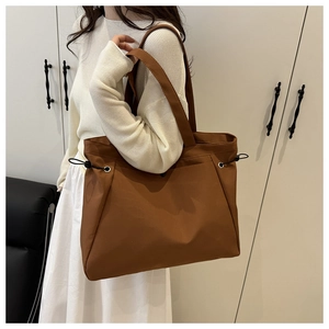 Detail view of caramel brown tote bag featuring side drawstrings and wide shoulder strap
